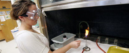 Student conducting chemistry experiment with bunsen burner.